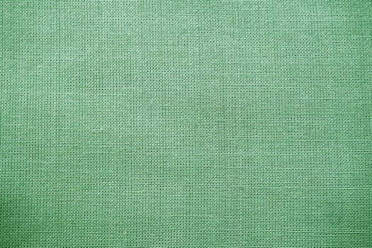 texture of natural green fabric close-up. The texture of the fabric is made of natural cotton or linen textile material. Green canvas background. Smooth surface, smoothed fabric.