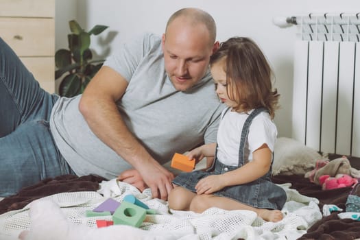 Dad and little girl 2-4 play with constructor sitting on floor at home