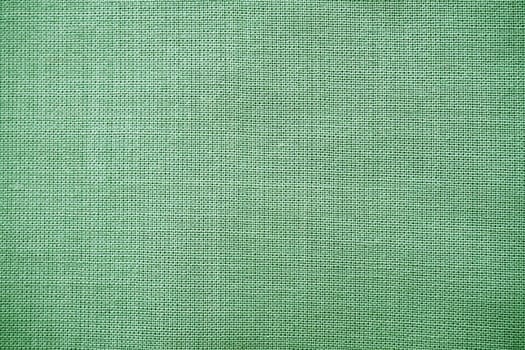 texture of natural green fabric close-up. The texture of the fabric is made of natural cotton or linen textile material. Green canvas background. Smooth surface, smoothed fabric.