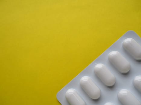 Heap of pills on yellow background. Tablets, vitamins and blisters with capsules for the treatment of diseases. Copy space