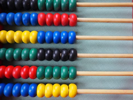 Education concept - abacus with many colorful beads. Red, blue, green, black, yellow details on the abacus. Mathematical exercises. School program.