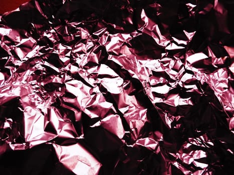foil close-up. Aluminum silver crumpled foil. Abstract metallic background. Foil for baking food. Background with a red or burgundy tint.