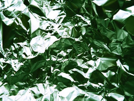 foil close-up. Aluminum silver crumpled foil. Abstract metallic background. Foil for baking food. Background with a green tint.