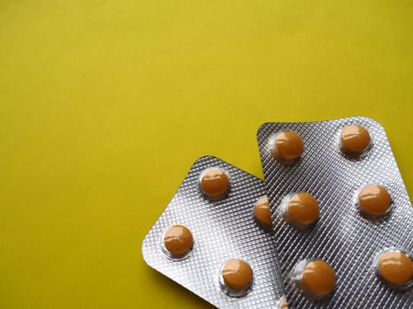 Heap of pills on yellow background. Tablets, vitamins and blisters with capsules for the treatment of diseases. Copy space