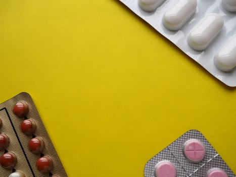 Heap of pills on yellow background. Tablets, vitamins and blisters with capsules for the treatment of diseases. Copy space