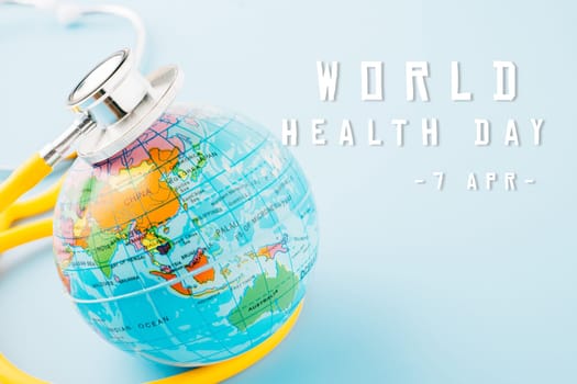 World Health Day. Yellow doctor stethoscope and world globe isolated on pastel blue background with copy space for text, Save world day, Green Earth Environment, Healthcare and medical concept