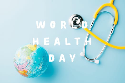World Health Day. Top view yellow doctor stethoscope wrapped around world globe isolated on pastel blue background with copy space for text, Global healthcare, Health care and medical concept