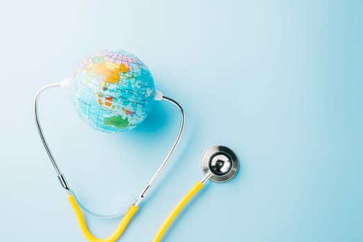 World Health Day. Top view yellow doctor stethoscope wrapped around world globe isolated on pastel blue background with copy space for text, Save world day, Health care and medical concept
