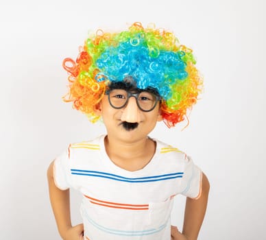April Fool's Day. Portrait of Funny kid boy clown wears a curly wig colorful a big nos and glasses and has a mustache isolated on white background with copy space, Happy child festive decor