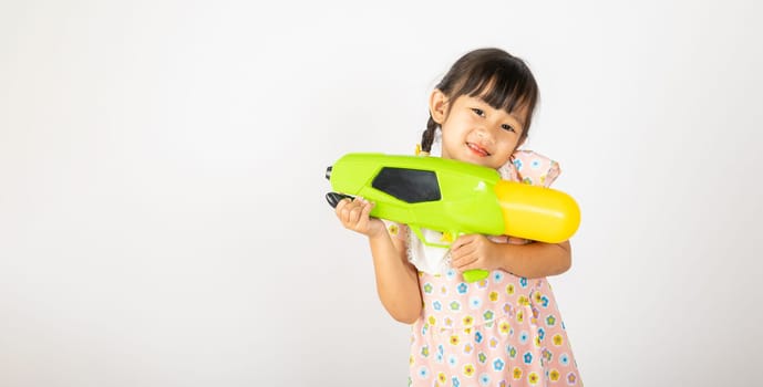 Happy Songkran Day, Asian little girl holding plastic water gun, Thai child funny hold toy water pistol and smile, isolated on white background, Thailand Songkran festival national culture concept