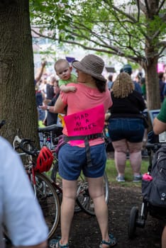 Philadelphia, PA / USA-06/25/2022: MAD AS A MOTHER woman with baby wears a feminist pro-choice sign at pro-abortion rally. Large crowd, cute baby, fabulous feminist image. Editorial use only.