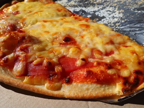 Pizza with tomatoes and cheese in a cardboard box and aluminum foil. Delicious pizza close up. Courier delivery of food to your home. Ordering pizza. Traditional Italian round yeast cake with filling.