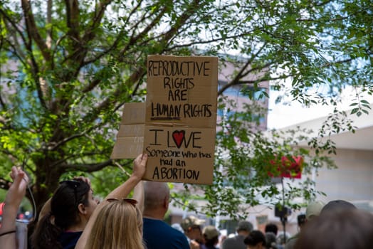 Young woman in a crowd holds up a protest sign at a political pro-choice rally REPRODUCTIVE RIGHTS ARE HUMAN RIGHTS and I LOVE SOMEONE WHO HAS HAD AN ABORTION. Josh Shapiro rally.