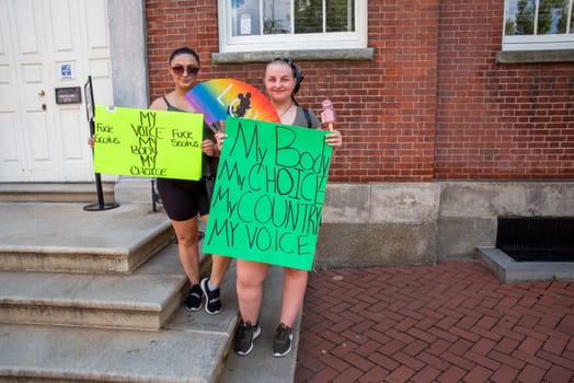 Philadelphia, PA USA 06-25-2022 Two young stand by historic buildings women with feminist pro-choice protest signs for a political rally.