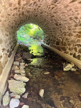 Beautiful architecture of antique stone arch bridge over a flowing Pennsylvania stream over colorful rocks and stones with no people and copy space