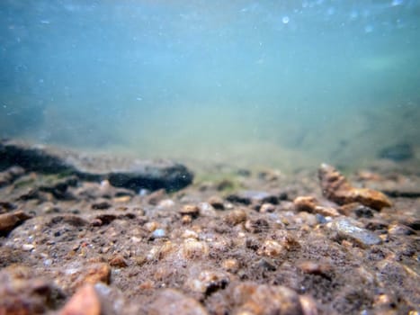 Blue-green flowing water ripples and bubbles over colorful textured rocks and silt in a clean beautiful Pennsylvania waterway. Serene image of healthy underwater environment. Great background with copy space and no people.