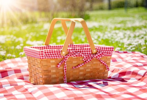 Picnic duvet with empty basket on the meadow in nature. Concept of leisure and family weekend.