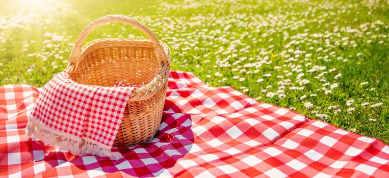 Picnic duvet with empty basket on the meadow in nature. Concept of leisure and family weekend.