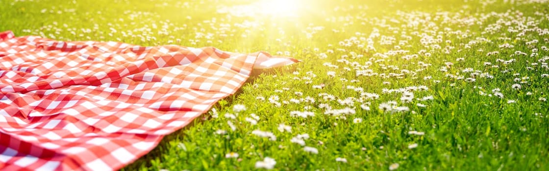 Picnic duvet on the meadow with green grass and spring flowers. Concept of tourism and leisure.