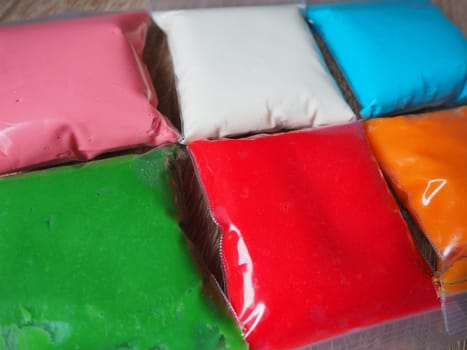 Colorful kid s plasticine on white background, Colorful dough modeling clay. Packing of colored soft plasticine in plastic bags.