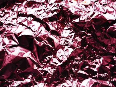 foil close-up. Aluminum silver crumpled foil. Abstract metallic background. Foil for baking food. Background with a red or burgundy tint.