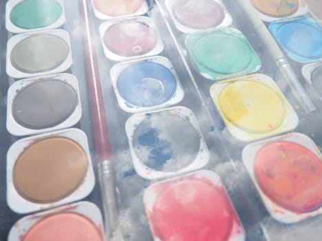 A set of watercolors of different colors for painting. Multi-colored round containers with bright paint. Tools for the lesson of drawing. Double composition. Clouds and sky. Painted clouds. Collage.