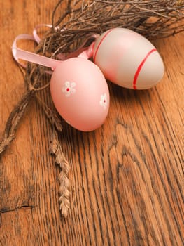Pink Easter eggs with decoration on a rustic wooden table background with space for text