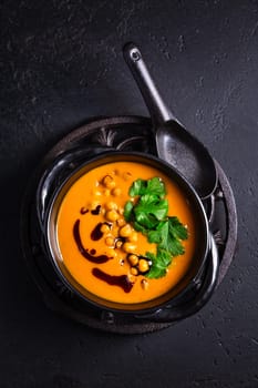 Creamy Pumpkin cream soup with pumpkin seed oil, baked chickpeas and cilantro