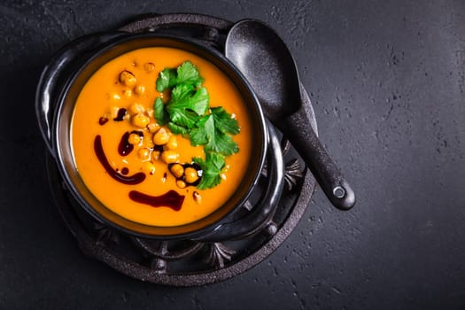 Creamy Pumpkin cream soup with pumpkin seed oil, baked chickpeas and cilantro
