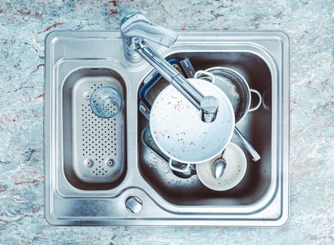 Dishwashing - pile of dirty dishes in kitchen sink