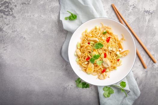 Stir fried noodles with chicken and vegetable in white bowl. Asian style food.