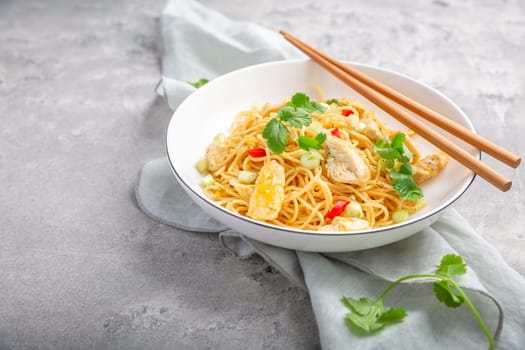Stir fried noodles with chicken and vegetable in white bowl. Asian style food.