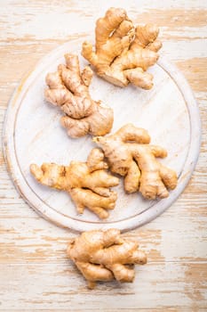 Ginger roots on white wooden background.