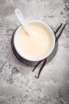 Homemade vanilla sauce in small bowl on grey background