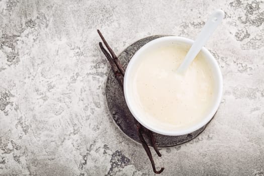 Homemade vanilla sauce in small bowl on grey background