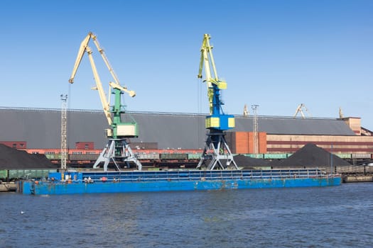 A dry cargo barge is loaded with coal at the port