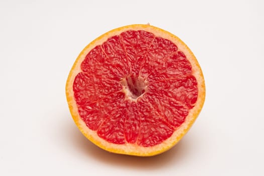 Sliced side of a grapefruit with red pulp isolated on a white background