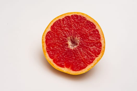 Sliced side of a grapefruit with red pulp isolated on a white background