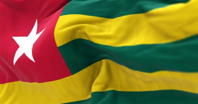 Togo national flag waving. Horizontal bands of green and yellow with a white star on a red square in the upper hoist-side corner. Fabric textured background. Selective focus. 3d illustration render