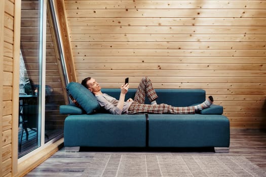 Middle-aged man on couch in his bungalow browsing internet, surfing web, using online app