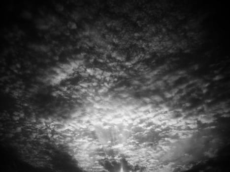 Sunset or sunrise. Clouds in the evening or morning sky. Sun rays. Beautiful landscape. Black and white monochrome photography in retro or vintage style. Increased level of photo noise as an art trick