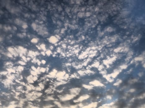 Clouds in the evening sky. The sun's rays pierce the clouds. Blue, yellow and orange colors of the sky and clouds. Beautiful landscape. The sun goes down.