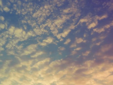 Beautiful, pink and yellow sunset in the sky. The clouds are colored by the low rays of the sun. Blue sky. Wonderful landscape