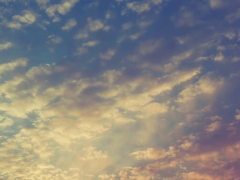 Beautiful, pink and yellow sunset in the sky. The clouds are colored by the low rays of the sun. Blue sky. Wonderful landscape