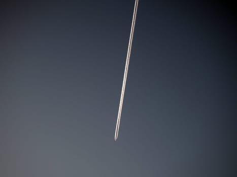 The trail from an airplane flying in the sky. Evening sky. Emissions of kerosene or heptyl rocket fuel. Environmental concept. Aviation business and passenger transportation. Vignetting.