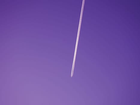 Airplane flying in the sky. Evening purple sky. Emissions of kerosene or heptyl rocket fuel. Environmental concept. Aviation business and passenger transportation.