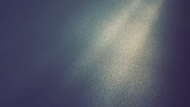 Oblique ray of light on a blue background. Blurred abstract backdrop with light effects and leaks. Side surface illumination. Divergent and asymmetric lines, stripes of light at angle. Yellowish glow