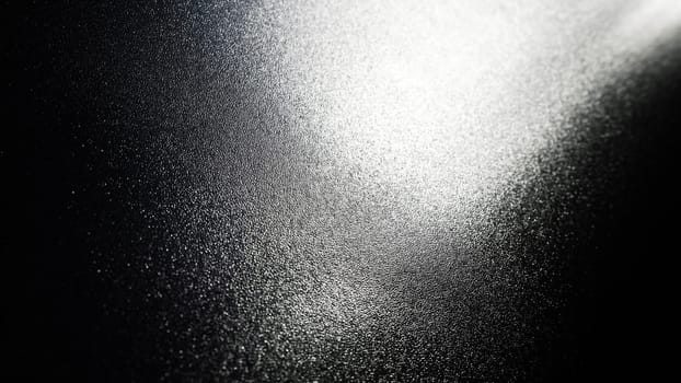 White bokeh and beam on a black background. Blurred glow from above on a dark surface. Night or space theme. Bokeh for the holiday. Abstract background. Glare, ray and light shine from above.