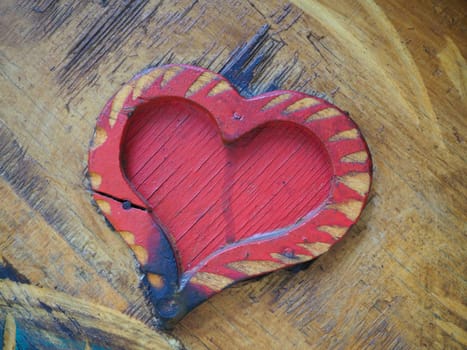 Carpentry heart shape on a wooden surface and painted red. A symbol of love and fidelity. Postcard for congratulations or recognition on Valentines Day. Signs of the influence of ignition or moisture