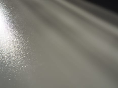 Diagonal rays of light on a gray background. Blurred abstract background light effect, light leaks. Side surface illumination. Small sparks and glow. Shine, glint or glare. Left top right down